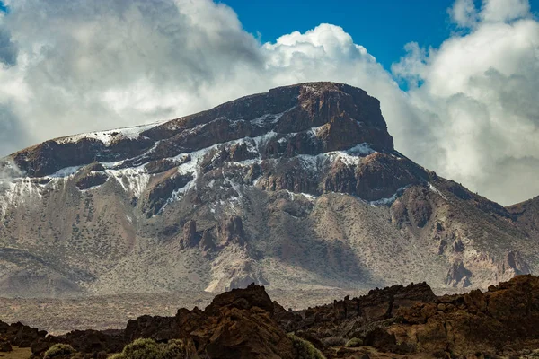 Mountain Teide med vita snö fläckar, delvis täckt av molnen. Klarblå himmel. Nationalparken Teide, Teneriffa, Kanarie öarna, Spanien. — Stockfoto