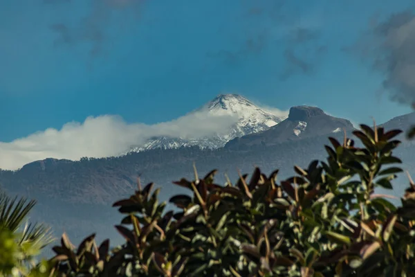 Berg Teide met witte sneeuw vlekken, deels bedekt door de wolken. Heldere blauwe hemel. Nationaal Park Teide, Tenerife, Canarische eilanden, Spanje. — Stockfoto