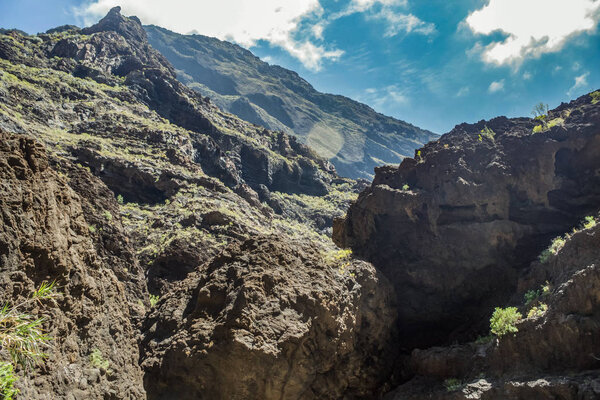 Rocks in the Masca gorge, Tenerife, showing solidified volcanic lava flow layers and arch formation. The ravine or barranco leads down to the ocean from a 900m altitude.