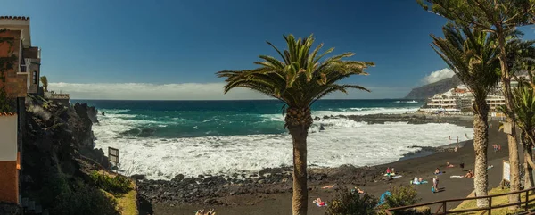 Escarpados acantilados de roca de lava. El océano turquesa descansa sobre un cielo azul brillante y una línea de nubes sobre el horizonte. Playa Arena, Tenerife. Amplio ángulo panorámico — Foto de Stock