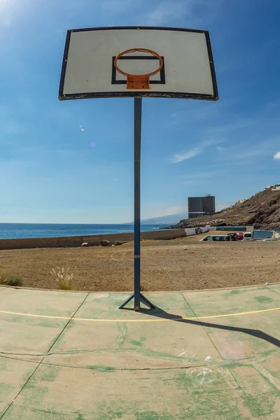 Eski spor sahasında sepetile basketbol backboard. Okyanusun önünde, arka planda terk edilmiş büyük bir bina. Tenerife. Geniş açı, balıkgözü lens. Dikey