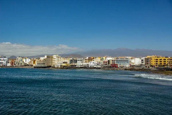 Granadilla de Abona, Tenerife'deki bohem El Medano köyünde, tatil otellerine, restoranlarına ve teraslarına doğru volkanik plajın geniş açılı panoraması.