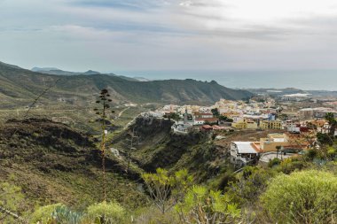 Tenerife güneyinde ünlü Hell gorge ve Adeje kasabanın havadan görünümü. Güneşli bir gün. Mavi gökyüzü ve dağların üzerinde bulutlar. Kuru dağ bölgesinde kayalık izleme yolu. Tenerife, Kanarya Adaları