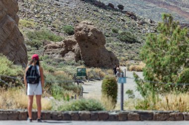 Ulusal Park Teide, Tenerife, İspanya - 11 Haziran 2015. Genç kız volkan Teide yakınlarındaki çok ünlü küçük kaya ilgi ile görünüyor. Milli parkta güzel lav manzara. Los Roques de Garcia