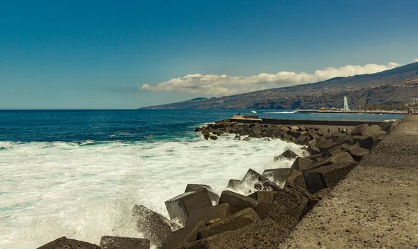 Puerto de la Cruz, Tenerife - 12 de abril de 2017: vista del paisaje urbano y la costa en un día soleado. Fuerte oleaje marino con enormes olas rompiendo en los bloques de piedra del muelle — Foto de Stock