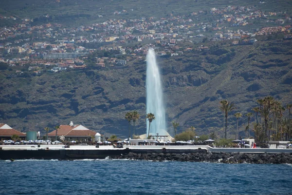 Puerto de la Cruz, Tenerife - 12 de abril de 2017: vista del paisaje urbano y la costa en un día soleado. Fuentes del Lago Martianez - famoso lugar para los turistas y la gente local. Lente de enfoque largo tiro — Foto de Stock