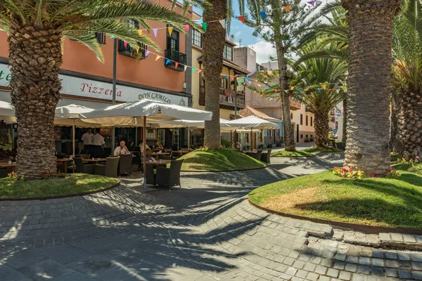 Puerto de la cruz, Teneriffa, Spanien - 10. Juli 2019: Bunte Häuser und Palmen auf den Straßen. Die Menschen entspannen sich und haben Spaß an einem warmen, sonnigen Sommertag. frühstücken, Kaffee trinken in einem gemütlichen Café — Stockfoto