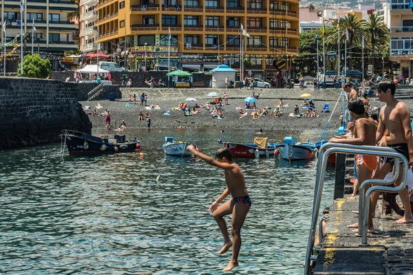 2019-01-12, Puerto de la Cruz, Santa Cruz de Tenerife. El puerto de Puerto de la Cruz es una atracción turística popular y lugar favorito para los lugareños. Los niños toman el sol y saltan desde el muelle — Foto de Stock