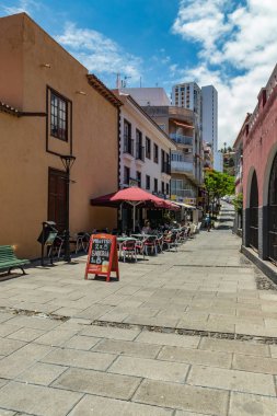 Puerto de la Cruz, Tenerife, Ispanya-10 Temmuz 2019: sokaklarda renkli evler ve palmiye ağaçları. İnsanlar dinlenmek ve sıcak güneşli bir yaz gününde eğlenin. Kahvaltı, rahat bir kafede kahve içmek