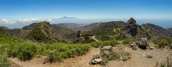 特内里费岛全景，地平线上方有泰德火山，在拉戈梅拉的加拉约奈国家公园附近有洛斯罗克斯山峰。在陡峭的绿色斜坡上，有遗物的桂冠和希瑟。金丝雀 — 图库照片