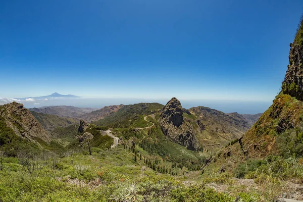 Panoramic view of Tenerife Island with volcano Teide above horizon and Los Roques peaks near Garajonay national park at La Gomera. Thickets of relic laurels and heather on steep green slopes. Canary — Stock Photo, Image