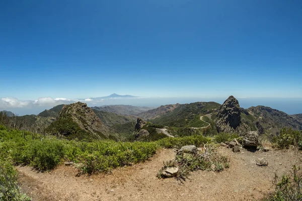 Panoramic view of Tenerife Island with volcano Teide above horizon and Los Roques peaks near Garajonay national park at La Gomera. Thickets of relic laurels and heather on steep green slopes. Canary — Stock Photo, Image