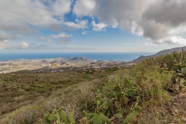 Köyün yukarısındaki dağlardan Los Cristianos ve turizm merkezi Las Amerika 'ya, Guaza dağ oluşumuna ve arka planda Tenerife' nin güney sahillerine doğru panoramik manzara