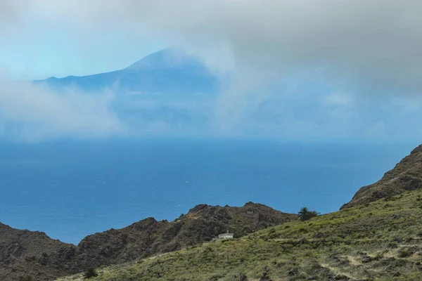 Blick auf Teneriffa durch niedrige Wolken. parque natural majona. Nordosten der Insel La Gomera. alte Vulkanberge mit grünem Gras, Lorbeeren und Heidekraut an steilen Hängen. Kanarische Inseln — Stockfoto