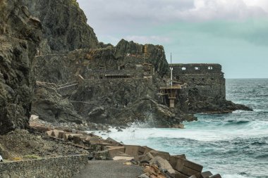La Gomera 'daki Vallehermoso plajında bazalt kayalara dev dalgalar çarpıyor. El Castillo del Mar adında eski bir muz fabrikası. Uzun odaklı mercekle çekilmiş. Kanarya Adaları, İspanya