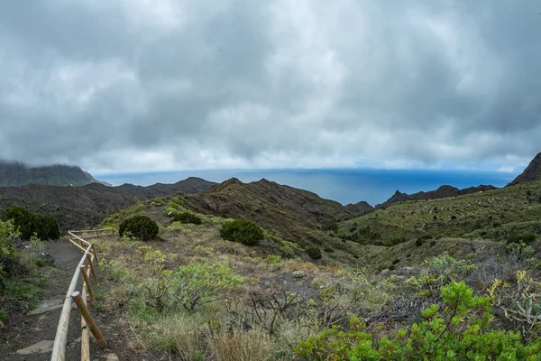 Narrow rural road in the mountains of Parque Natural Majona. Low wet clouds hanging over the green slopes. View of the north-eastern part of La Gomera island. Canary Islands, Spain — Stockfoto