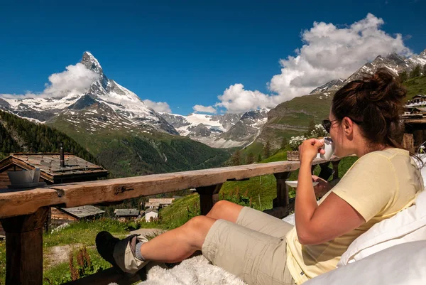 Kadın turist zevk sabah görkemli Matterhorn güzel bir görünümü ile kahve. Valais Alpler ziyaret ve Zermatt yürüyüş.