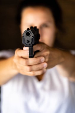 Elinde bir silah ve bir kamera doğru amaçlayan genç kadın. Tabanca el ve işaret.