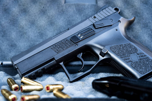 Close up view of bullets and handgun. Small black pistol next to a 9 mm bullets and a magazine. Shallow depth of field.