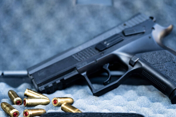 Close up view of bullets and handgun. Shallow depth of field. Pistol out of focus.