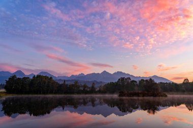 Sabah erken atış güzel sonbahar dağ manzarası göl, renkli ağaçlar ve yüksek tepeler ve Kızıl gök yüksek Tatras, Slovakya ile huzurlu sahnenin.