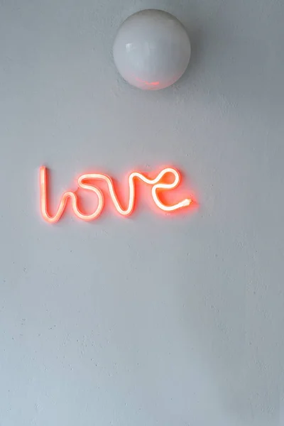 Red Neon Love Sign on a white wall. Selective focus.