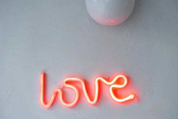 Red Neon Love Sign on a white wall. Selective focus.