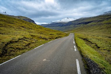 Faroe Adaları 'nın dramatik manzarası. Dağların ortasında ücra bir yol var..
