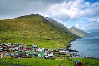 Faroe Adaları 'ndaki pittoresk İskandinav köyünün dramatik manzarası. Faroe Adaları 'nda karla kaplı dağlar ve derin dar fiyortlarla çevrili uzak bir yerleşim yeri..