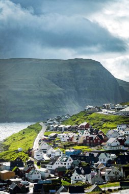 Faroe Adaları 'ndaki pittoresk İskandinav köyünün dramatik manzarası. Faroe Adaları 'nda karla kaplı dağlar ve derin dar fiyortlarla çevrili uzak bir yerleşim yeri..