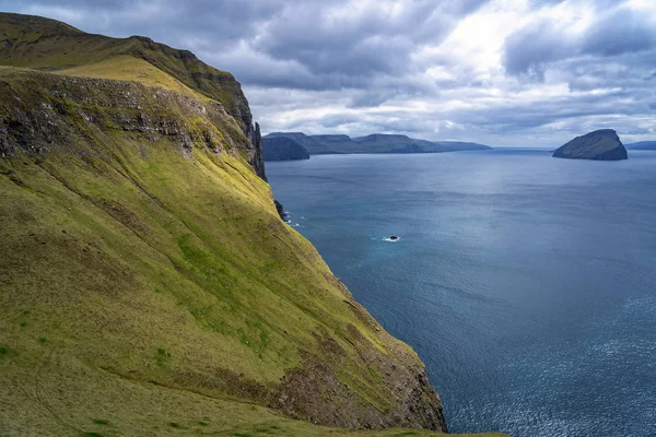 Fırtınalı havada çim çayırları ve kayalık uçurumlarla Faroe Adaları 'nın dramatik manzarası.