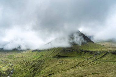Faroe Adaları 'ndaki bulutlarla kaplı dağların muhteşem manzarası..
