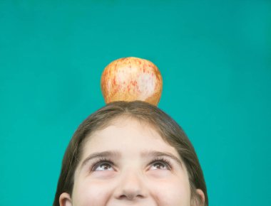 chica observa una manzana que tiene en su cabeza