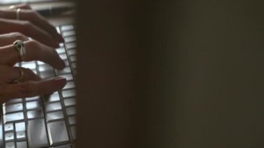 desplazamiento de derecha a izquierda de la camara donde se observa las manos de una mujer tecleando una computadora en plano cerrado
