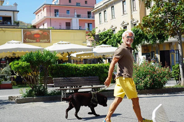 Usměvavý starší, chodící jeho pes v centru Trohráku v italské Kalábrii v srpnu, 2019 — Stock fotografie