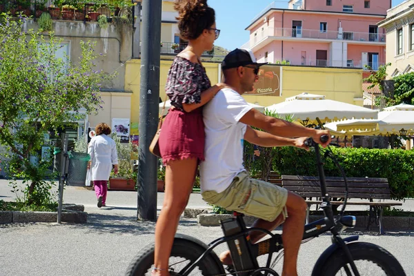 Ένα νεαρό ζευγάρι που ιππεύει με ένα e-bike μαζί, το κορίτσι που στέκεται πίσω από τον αναβάτη — Φωτογραφία Αρχείου