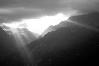 Siyah ve beyaz fotoğraflarla parlayan güneş ışınlarıyla dramatik bir gökyüzü..