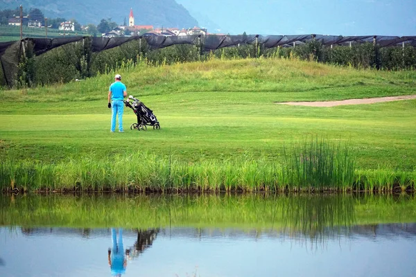 Golfista z wózkiem golfowym obserwujący partnera. — Zdjęcie stockowe