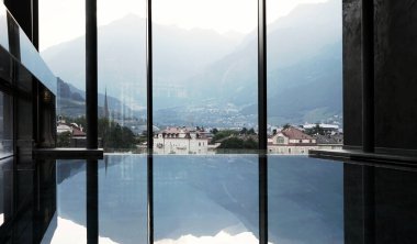 Merano, Güney Tirolean şehri ve İtalyan Alpleri manzarası, lüks bir kapalı havuzun içindeki dağlar.