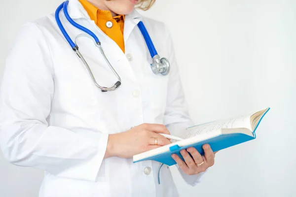 Kadın doktor hastanedeki panoya notlar yazıyor. Stetoskop ve not defteri olan beyaz önlüklü bir doktor..