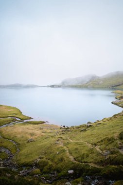 Sisli bir günde dağdaki yüksek irtifadaki gölde sohbet eden üç arkadaş