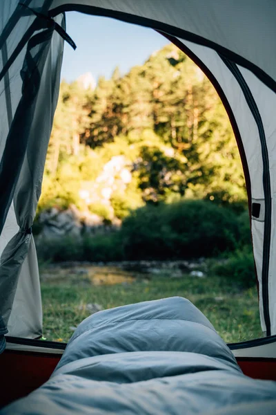 View from the inside of a tent next to a river