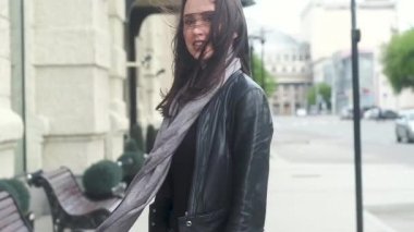 uzun koyu saçlı güzel neşeli genç kız, gri eşarp, siyah deri ceket ve kot pantolon. Çerçeveye bakar, gülümser, arkasını döner ve bir şehir sokağına gider. Rüzgarda çırpınan uzun saçlar