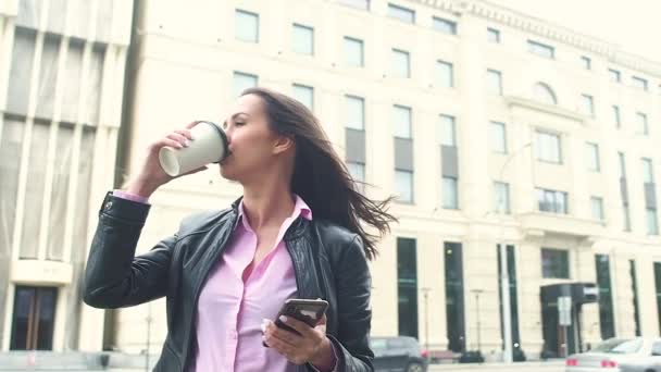 컵에서 커피를 마시는 도시의 배경에 아름다운 비즈니스 바람이 그녀의 머리를 — 비디오