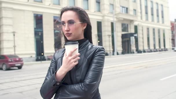 선글라스에 여자입니다 거리에 거리를 들여다보고 컵에서 커피를 마시고 있습니다 바람이 — 비디오