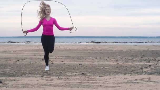 Menina Tênis Branco Perneiras Pretas Rosa Shirt Pulando Corda Praia — Vídeo de Stock