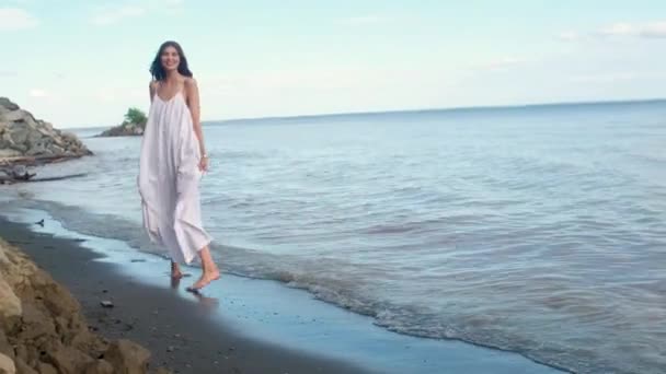 해변에 드레스에 맨발과 머리를 아름다운 카메라에 이야기하고 화창한 여름날 바닷가 — 비디오