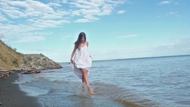 해변에 드레스에 머리와 아름다운 날씬한 소용돌이를 가지고 튀김을 만드는 일몰에 — 비디오