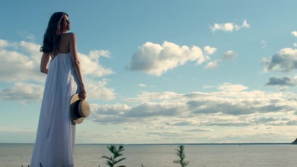 Hermosa Chica Delgada Vestido Largo Blanco Sostiene Sombrero Paja Mano — Vídeos de Stock