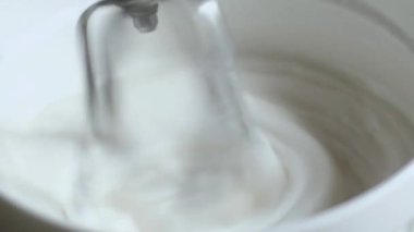 şekerleştirici, dönen metal Bıçaklar ile krema elektrik karıştırıcı derin bir kase dışarı çeker. kalın sos aşağı damlama. mutfak arka planda doğal ışık ile çekim.